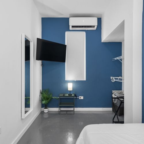 Nuestra habitación cuenta con una acogedora cama con sábanas blancas impecables contra una pared decorativa en azul intenso, lo que ofrece un refugio tranquilo para los exploradores de la ciudad.