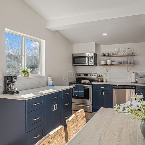- whip up meals in this bright kitchen with navy cabinetry and stainless steel appliances
- enjoy natural light streaming through the window while sipping your morning coffee
- gather around the dining table with woven chairs for cozy shared meals