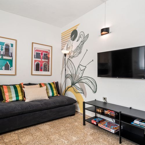 Entertainment Hub: Relax and enjoy your favorite shows on the wall-mounted flat-screen TV in our comfortable living area, complete with a cozy sofa and artistic touches.