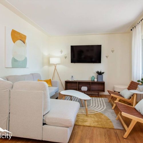 - comfy sectional and leather woven chairs invite you to relax and unwind
- large tv, textured rug, and warm wood floors set the tone for movie nights
- light walls and playful art bring charm to this cozy gathering space