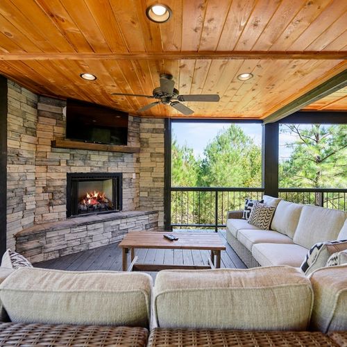 The outdoor covered patio with an oversized outdoor sectional around a fireplace.