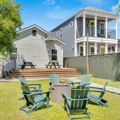 Bright backyard hangout w/ firepit, Adirondack chairs, & sunny NOLA skies overhead.