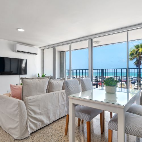 Spacious living room with L-shaped sofa, coffee table, arcade game, and open view to kitchen and dining area.