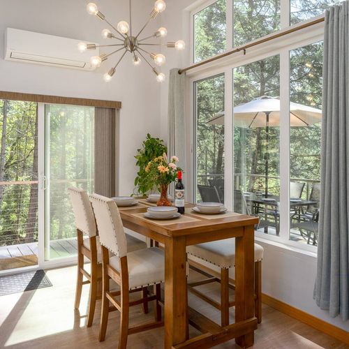 Dinner for four with a forest backdrop — the dining table opens straight onto the upper deck for seamless indoor-outdoor living.