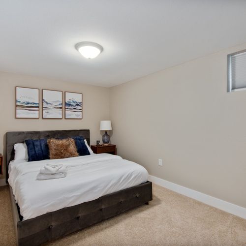 The lower level bedroom is fitted with a queen size bed, matching nightstands with accent lamps, and a closet for extra storage space.