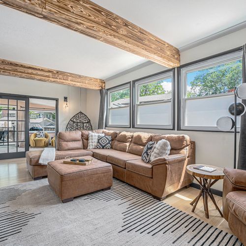 Relax in the comfortable living area off the kitchen, featuring a large l-shaped sectional, rustic wood beams, and a unique swinging chair.