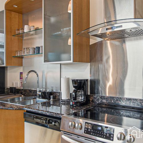 - prep your meals with ease at this modern setup with deep sink and glass cooktop
- open cabinets display dishes and glasses for added convenience
- coffee maker, oven, and dishwasher make this kitchen as practical as it is sleek