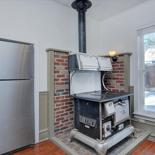 - discover rustic charm with a rare antique cast iron stove framed in brick
- sunlight pours through tall windows, blending nostalgia with natural light
- modern stainless steel fridge offers convenience beside vintage flair