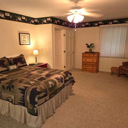 Bedroom #1:  the cabin has a large primary bedroom with a queen-size bed, desk, comfy chair, ceiling fan, dresser, and closet.