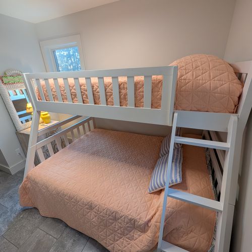 BEDROOM #2 (MAIN FLOOR):  Features a twin-on-full bunk bed, ceiling fan with safety guard, dresser, mirror, closet, and lamp.