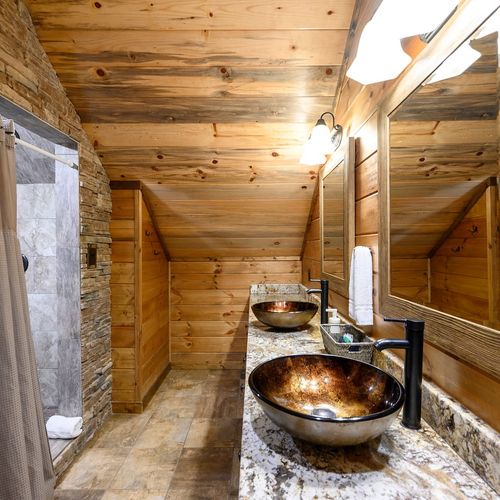 Shared bathroom with bunk room has double vanity and walk-in shower.