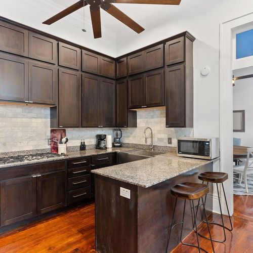 Fully stocked kitchen w/ granite counters, dark cabinetry & bar seating for casual bites.