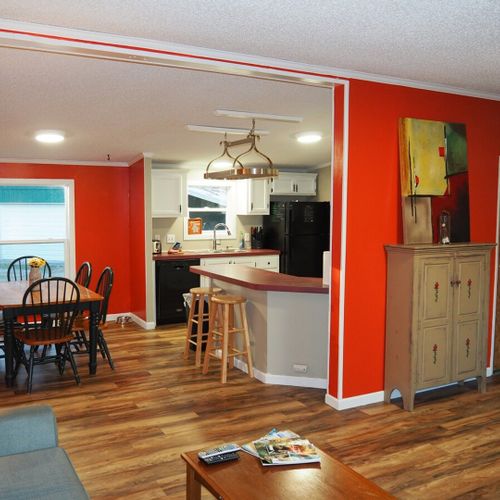 A constructive photo from near the front door that shows the living room, dining room, entrance to the kitchen, a closet door (door on the left), and the door to the master bedroom (door on the right).