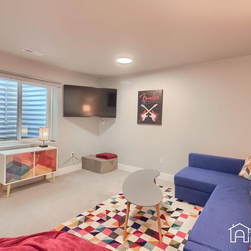 - watch your favorite shows on the wall mounted tv from the comfort of a bold blue sofa
- decorative console, bean bag, and modern lighting add playful charm
- window well brings in natural light while maintaining privacy downstairs
