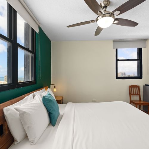 The room features a queen-size bed for comfortable sleep and combines green accents with modern elements, offering a peaceful yet stylish ambiance.