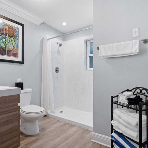 Bright bathroom w/ walk-in shower & neatly stocked essentials.