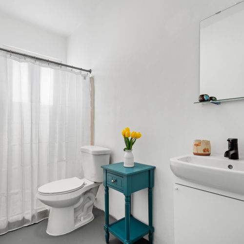 Refresh and rejuvenate in our sleek, white bathroom, complete with a stylish teal accent table and cheerful yellow florals.
