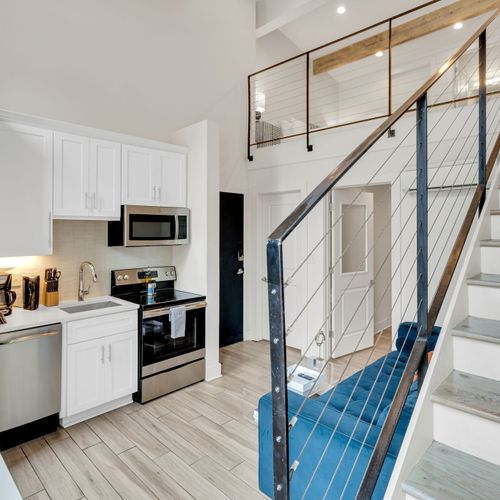 Sleek kitchen & staircase flow seamlessly into the bright, open main space.