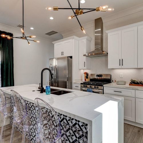 Clean white kitchen w/ gas stove, stainless fridge & generous counter space.