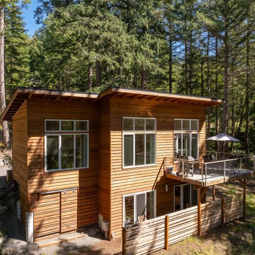 "Two levels of living, one unforgettable setting — the upper deck with patio umbrella is your perch above the Orcas Island forest.