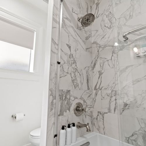 Elegant bathroom w/ marble-look walls & a sleek shower.