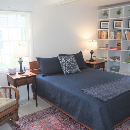 Bedroom #2 (main floor):  large and lovely bedroom with a queen-size bed, rocking chair, nightstands with lamps, two bookcases, a dresser, and a wardrobe.