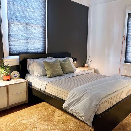 Cozy bedroom w/ a made bed, soft linens & warm, moody tones.