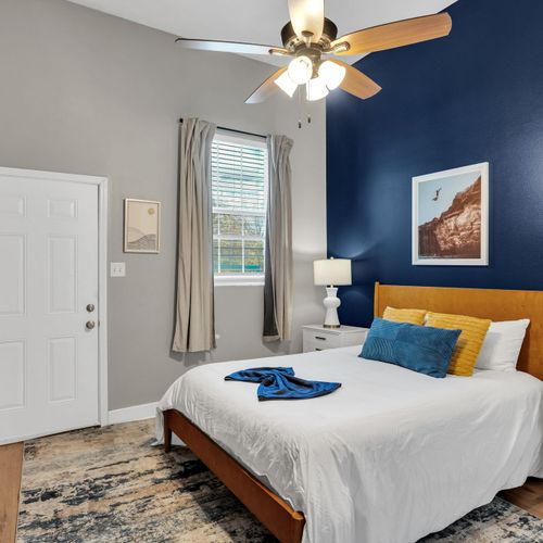 Serene bedroom w/ bold navy walls & a plush bed dressed in blue & gold.