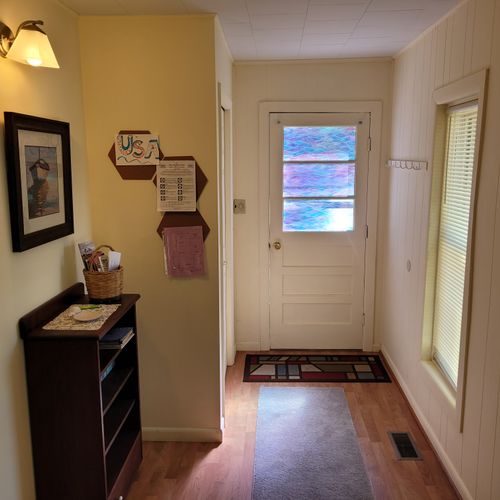 Living room:  features a loveseat, comfy chairs, live-streaming television with roku, and a ceiling fan.