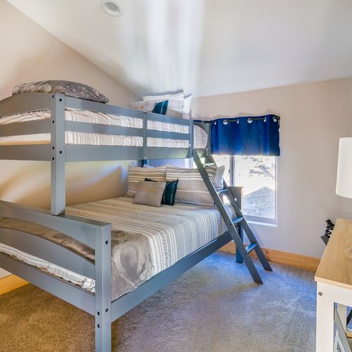 This bedroom features a twin over a queen bunk bed, a closet and a lovely view out to the mountains.