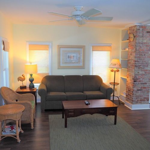 Living room: the apartment has a cozy living room with a sofa, chair, ceiling fan, and live streaming television.