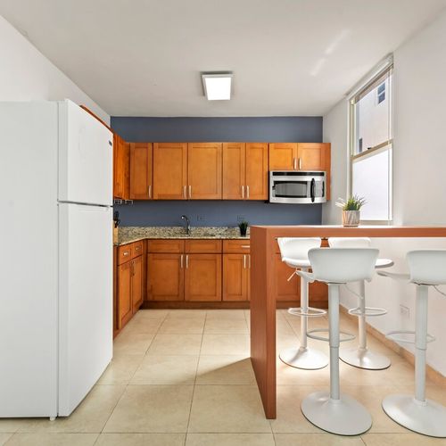 Step into a bright and welcoming kitchen, where the morning sun illuminates a space equipped with modern amenities and a cozy breakfast bar for two.