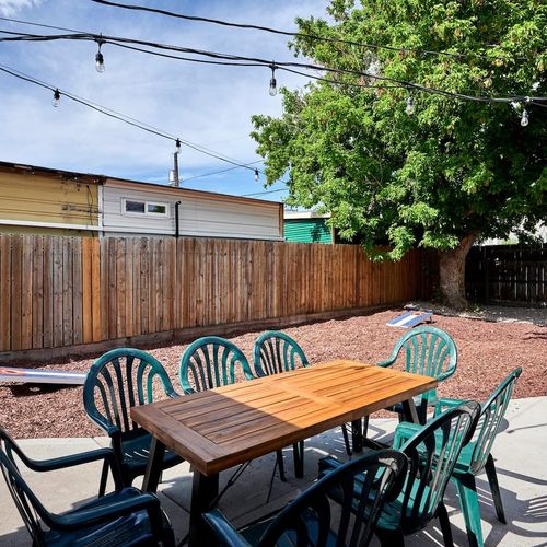 - backyard setup with a wooden dining table and plenty of seating for groups
- string lights overhead create a festive vibe for meals and outdoor fun
- spacious fenced yard with a mature tree and cornhole for casual games