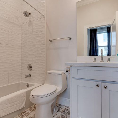 Well-lit bathroom w/ a classic tub & vanity, fresh & functional.