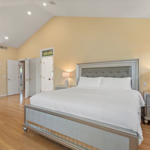 Spacious room featuring plush king bed, dual nightstands, and sunny tree‑line view.