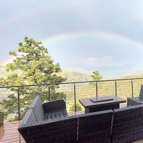 - witness nature’s magic with moments like this rainbow over the forested valley
- fire table adds warmth while the mountains provide a dramatic backdrop
- relax on cushioned seating as you soak in the view and maybe even spot a rainbow
