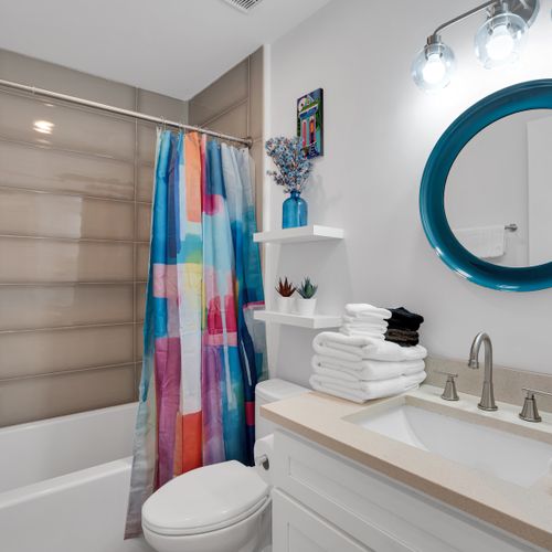 Bathroom w/ a sink, colorful shower curtain & tiled walls.