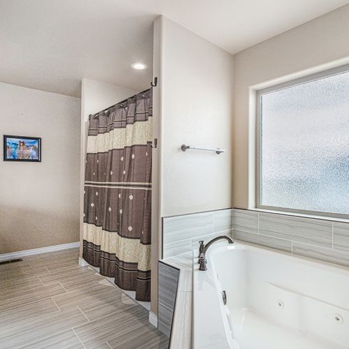 This ample bathroom offers a deep tub for relaxing and a grand mirror to enhance the space.