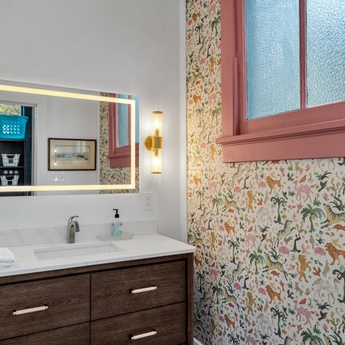 Warm, moody bathroom w/ backlit mirror & a sink w/ clean lines.