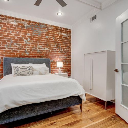 Cozy first bedroom w/ a queen bed & soft, relaxed lighting.