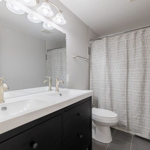 - spacious bathroom with dual sink vanity, bright lighting, and a tiled tub shower combo
- sleek black cabinetry and brushed nickel fixtures elevate the clean modern look
- perfect for sharing with plenty of counter space and storage for everyone