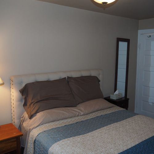 Bedroom #1:  features a queen-size bed, mirror, nightstands, lamps, dresser, chair, and television.