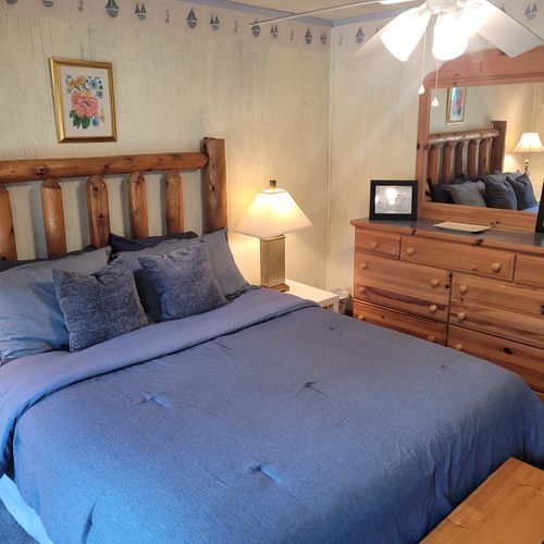 BEDROOM #1 (MAIN FLOOR):  Features a queen-size bed, dresser, mirror, closet, rocking chair, private ensuite bathroom, and private live-streaming television.  (Note that there is a collapsing curtain between the bedroom and the living room.)