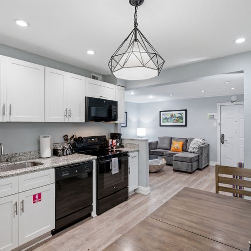 Whip up home-cooked meals in this modern kitchen w/ white cabinetry & black appliances.
