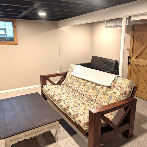 LIVING ROOM #3 (LOWER LEVEL):  Very fun third living room / game room in the basement with a futon, loveseat, coffee table, electric fireplace, and large screen smart television with live streaming. Note that this room is not to be used for sleeping.