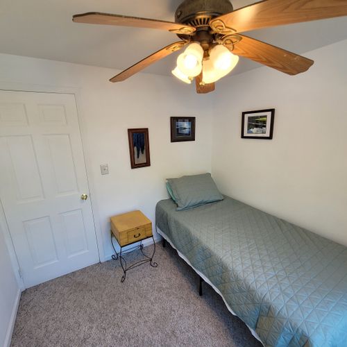 Bedroom #3 (second floor):  features a twin bed, ceiling fan, and a pedestal fan.