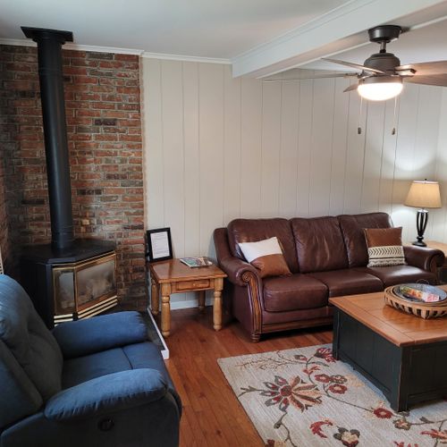 Living room:  comfy living room with a sofa, gas fireplace, live streaming television, coffee table, comfy chair, and ceiling fan.