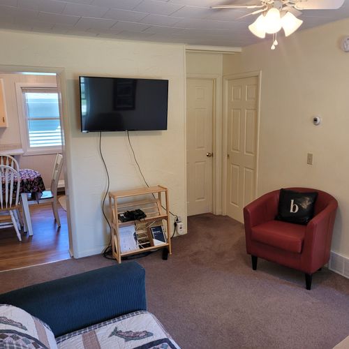 Living room:  features a loveseat, comfy chairs, live-streaming television with roku, and a ceiling fan.