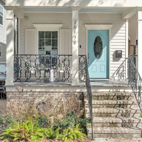 Classic New Orleans façade w/ ironwork details & a charming teal front door.