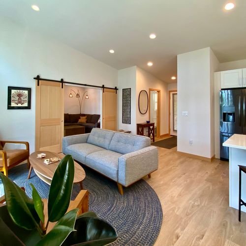 Sun-drenched open living with mid-century style, sliding barn door, and a fully equipped kitchen just steps away